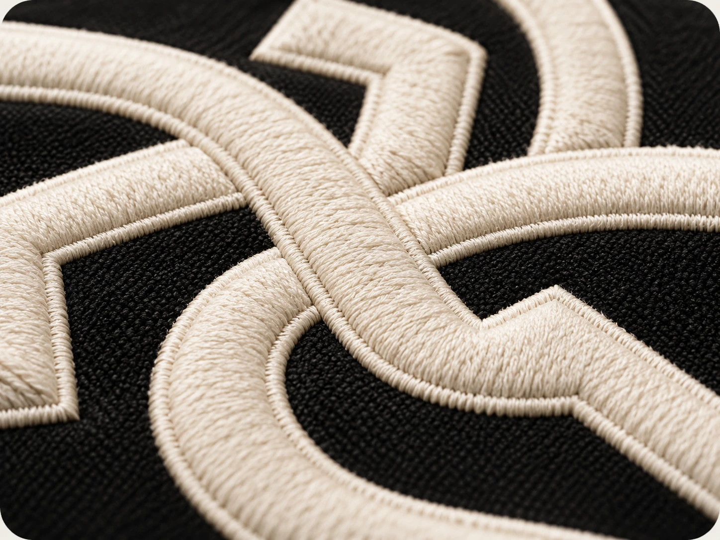 Close-up of dense cream embroidery stitches on black fabric