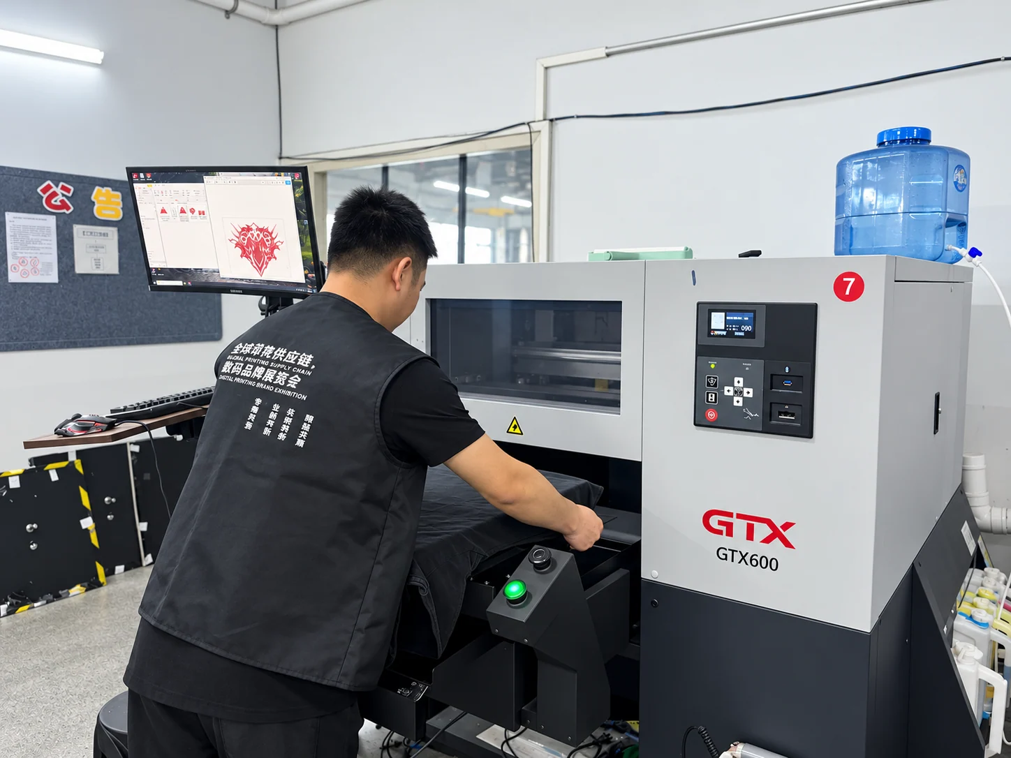 An operator positioning a black garment on a GTX600 garment printer.